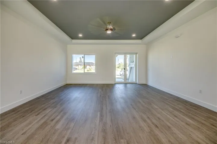 Unfurnished room featuring a raised ceiling, recessed lighting, and wood finished floors