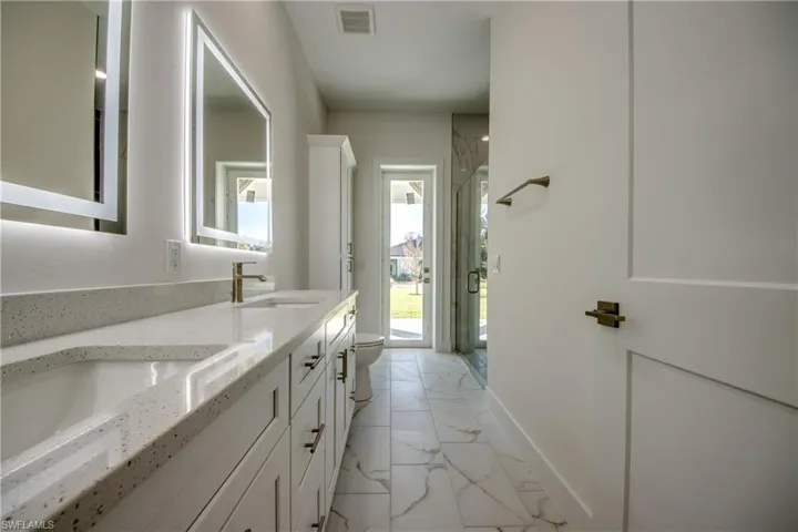 Full bathroom with a shower stall, double vanity, and light marble finish floors