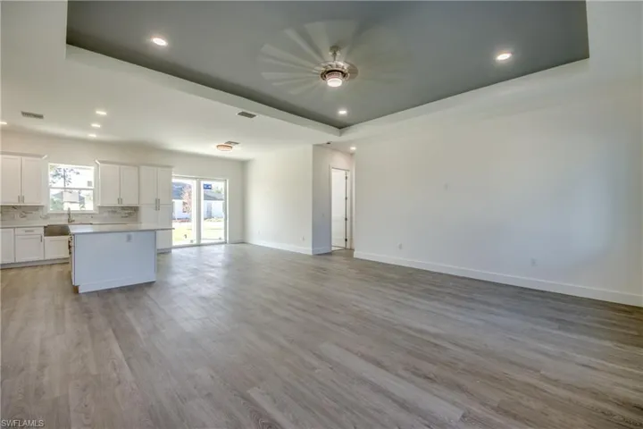 Unfurnished living room with a raised ceiling, light wood-style floors, and recessed lighting