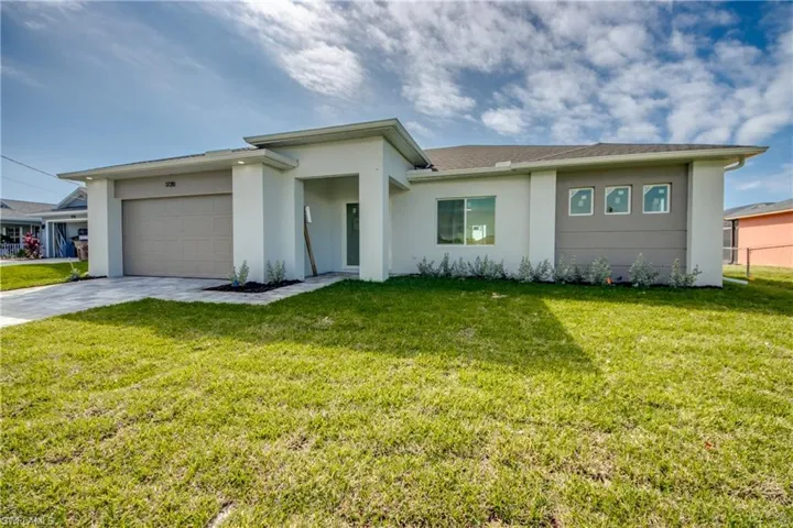 View of front of home featuring a front lawn, stucco siding, an attached garage, and concrete driveway