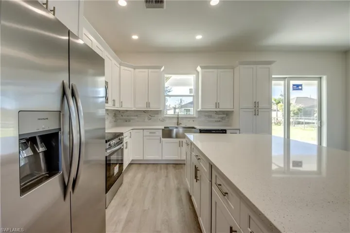 Kitchen with stainless steel appliances, white cabinets, tasteful backsplash, light stone counters, and recessed lighting
