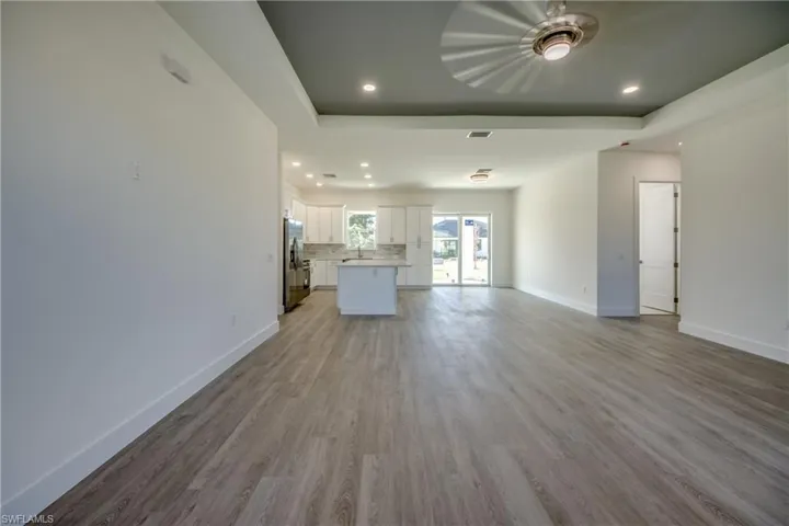 Unfurnished living room featuring recessed lighting, light wood-style floors, and a tray ceiling