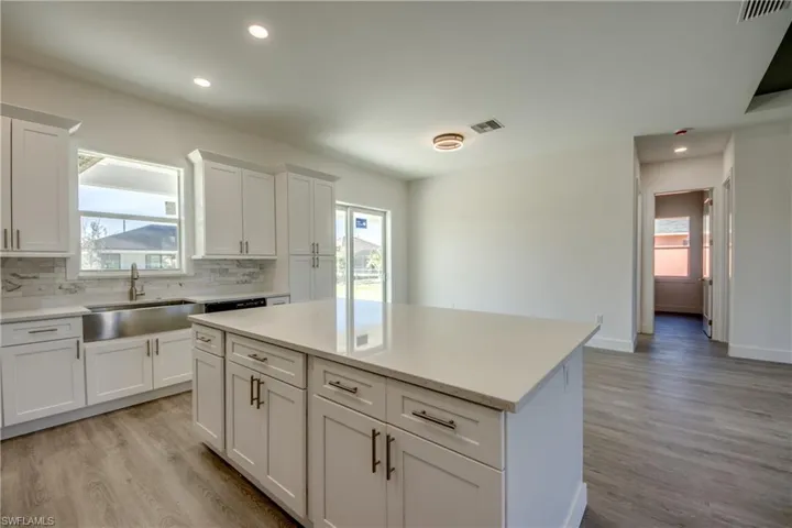Kitchen with white cabinetry, a kitchen island, recessed lighting, light wood-type flooring, and backsplash