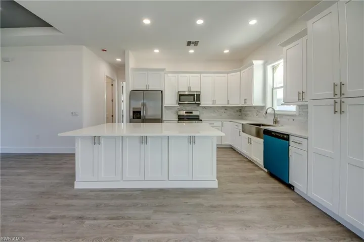 Kitchen featuring appliances with stainless steel finishes, decorative backsplash, white cabinets, light wood-style flooring, and recessed lighting