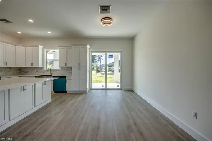 Kitchen featuring white cabinetry, decorative backsplash, recessed lighting, dishwashing machine, and light wood-style floors