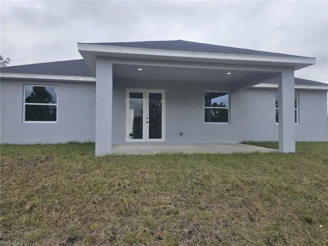 Back of house featuring a patio area, a lawn, and french doors
