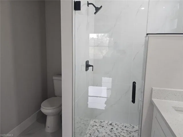 Bathroom featuring toilet, an enclosed shower, and vanity