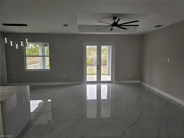 Spare room featuring ceiling fan, french doors, and a raised ceiling