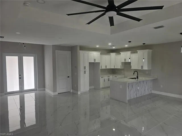 Kitchen with white cabinetry, french doors, sink, a raised ceiling, and kitchen peninsula
