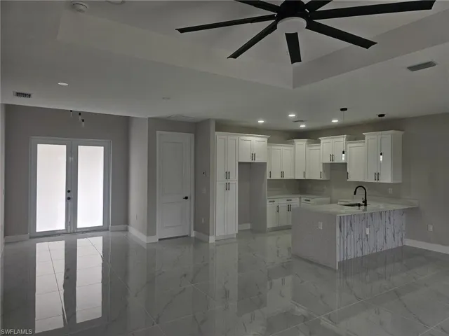 Kitchen with kitchen peninsula, a raised ceiling, sink, french doors, and white cabinets
