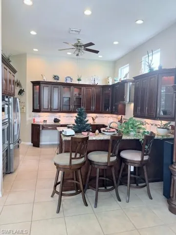 Kitchen featuring backsplash, recessed lighting, a ceiling fan, dark brown cabinets, and light tile patterned flooring