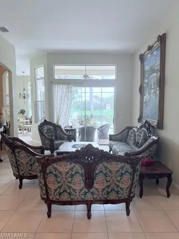 Living room with arched walkways, light tile patterned floors, and a chandelier