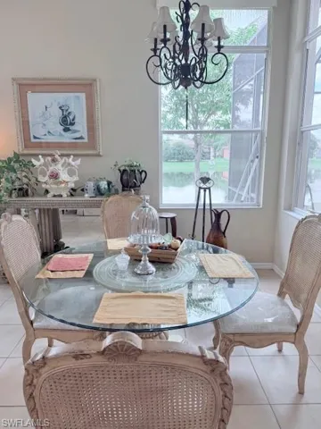 Dining area with light tile patterned flooring, a chandelier, and healthy amount of natural light