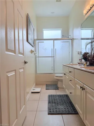Full bathroom with tile patterned flooring, vanity, and bath / shower combo with glass door