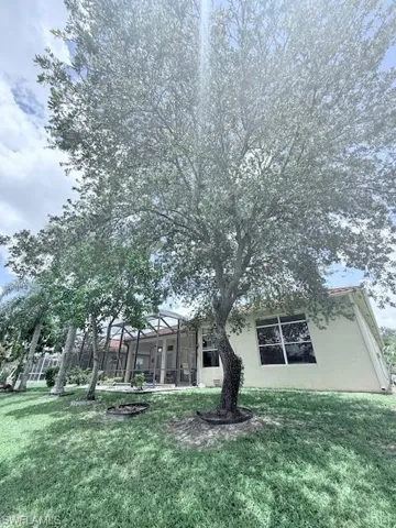 Back of property with a yard, stucco siding, and glass enclosure