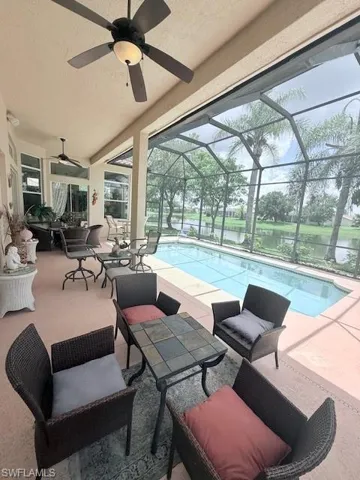 Outdoor pool featuring an outdoor hangout area, a ceiling fan, glass enclosure, a patio area, and a water view