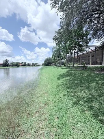 View of green lawn featuring a water view and a lanai