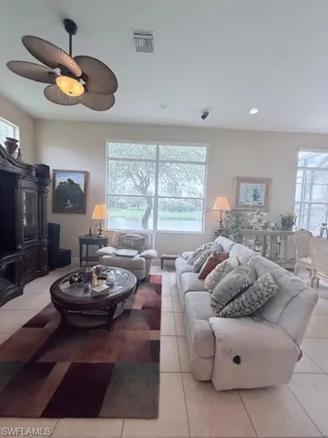 Tiled living room with a ceiling fan, plenty of natural light, and recessed lighting