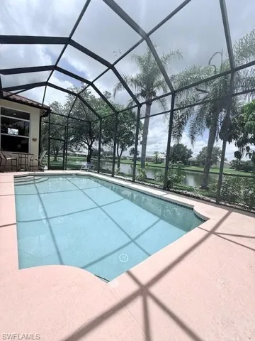 Swimming pool with a patio, glass enclosure, and a water view
