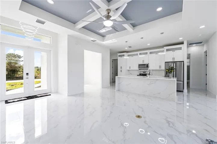 Unfurnished living room with a tray ceiling, french doors, ceiling fan, and light tile floors