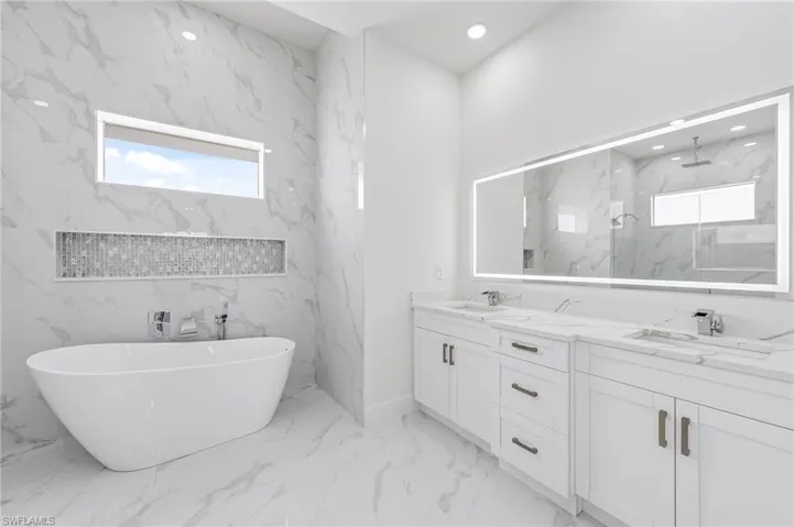 Bathroom featuring tile walls, tile floors, a wealth of natural light, and dual sinks