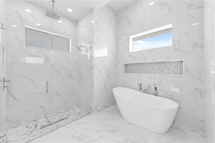 Bathroom featuring shower with separate bathtub, tile flooring, and tile walls