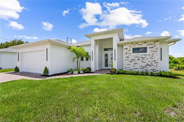 View of front facade featuring a garage and a front lawn