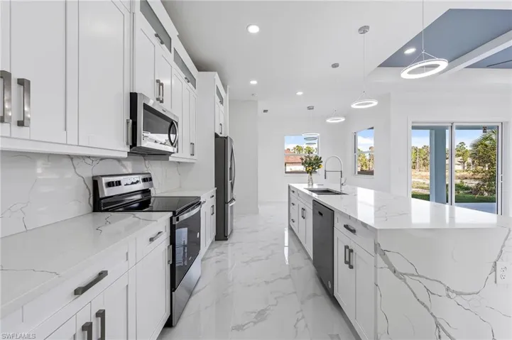 Kitchen with appliances with stainless steel finishes, sink, light tile floors, and hanging light fixtures