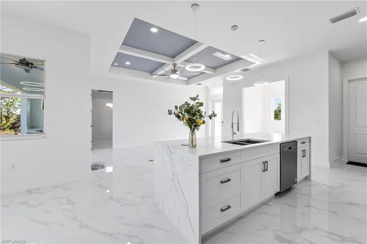 Kitchen with coffered ceiling, hanging light fixtures, ceiling fan, white cabinetry, and sink