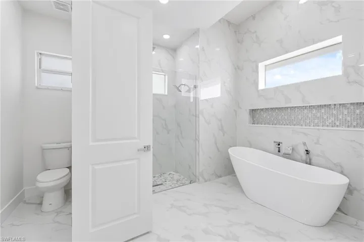 Bathroom featuring tile walls, tile flooring, independent shower and bath, and toilet