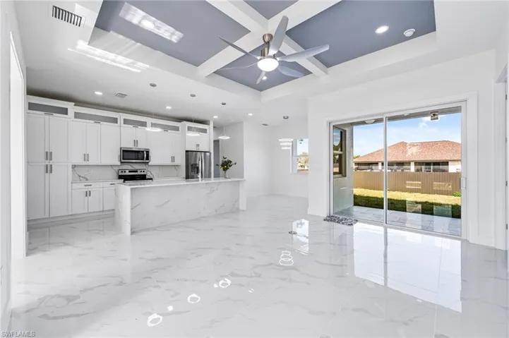 Kitchen featuring ceiling fan, a raised ceiling, white cabinetry, appliances with stainless steel finishes, and light tile floors