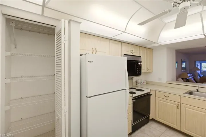 Kitchen featuring freestanding refrigerator, light brown cabinets, electric range oven, ceiling fan, and light countertops