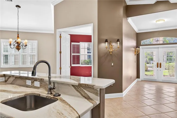 Kitchen featuring ornamental molding, french doors, light stone countertops, hanging lights, and light tile patterned flooring