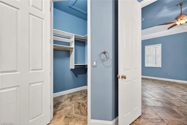 View of primary walk in closet with built in shelving