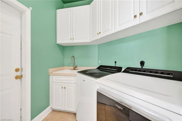 Laundry area featuring washer and clothes dryer, cabinet space, and light tile patterned flooring