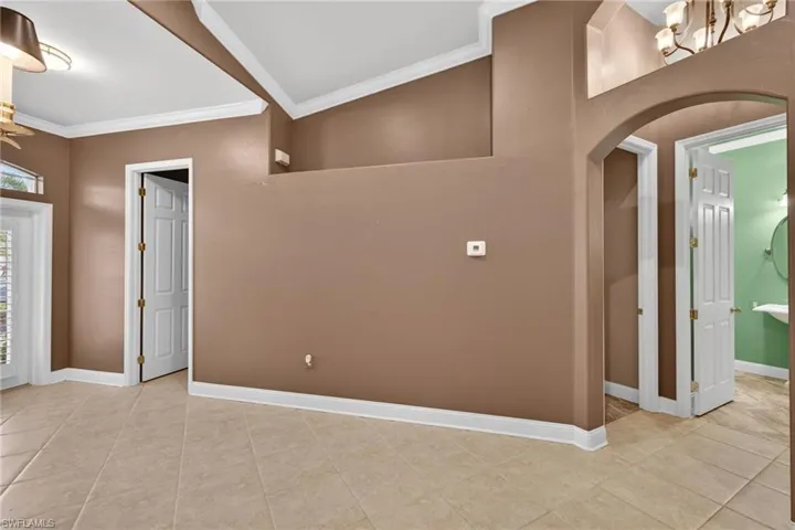 Entrance foyer featuring ornamental molding, suspended lighting, light tile patterned flooring, and arched walkways