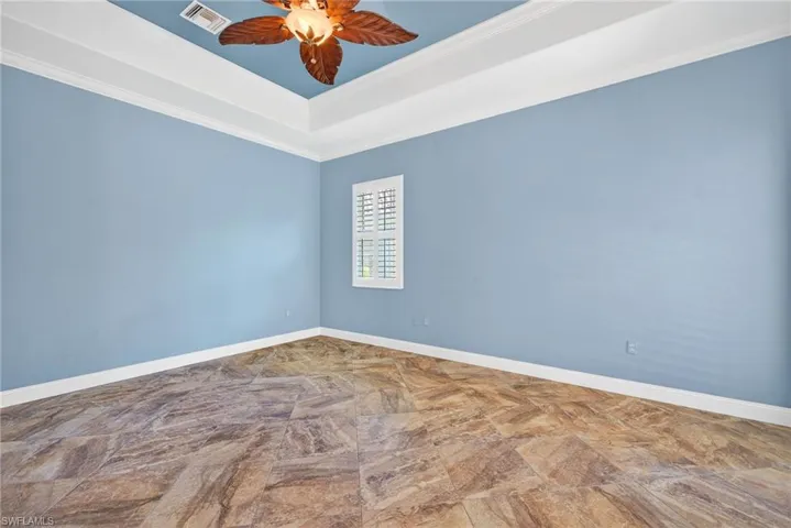 Spare room with a raised ceiling, ceiling fan, and crown molding