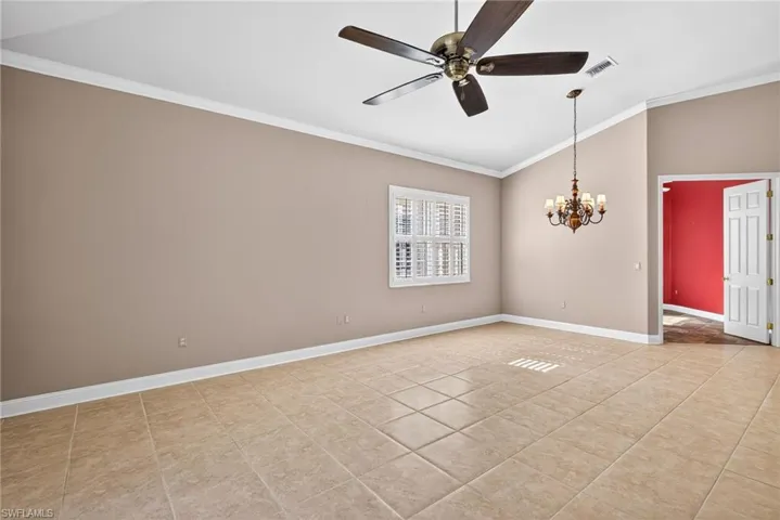 Unfurnished room featuring lofted ceiling, ornamental molding, a ceiling fan, hanging lights, and light tile patterned flooring