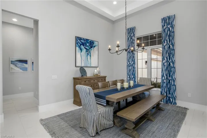 Formal dining room near the entry with designer lighting, transom windows, coffered ceiling, and custom window coverings.