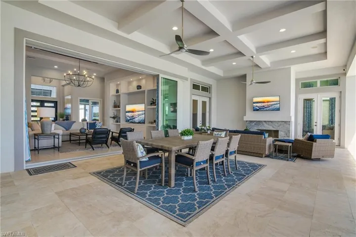 Dining room with a high end fireplace, built in shelves, ceiling fan with notable chandelier, and a wealth of natural light