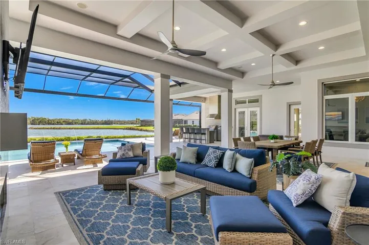 View of patio / terrace featuring an outdoor living space, ceiling fan, a water view, glass enclosure, and an outdoor bar