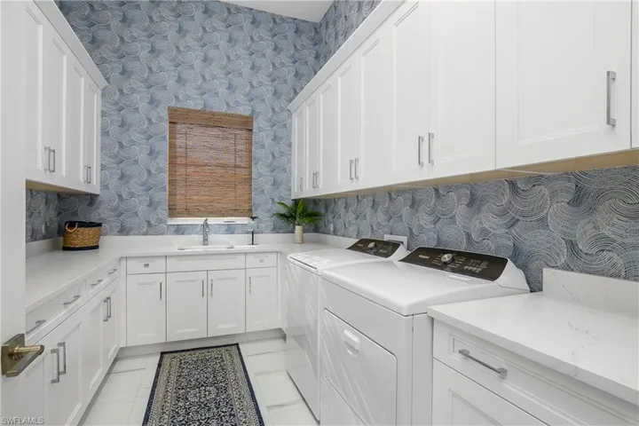 Laundry room with custom wallpaper and plenty of cabinet space for extra storage.
