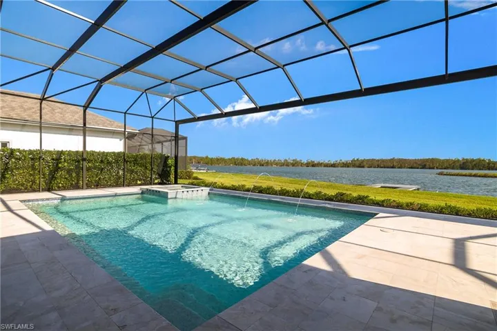 View of swimming pool with a lanai, pool water feature, a patio area, an in ground hot tub, and a water view
