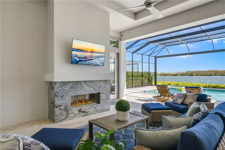 View of patio / terrace with an outdoor living space with a fireplace, pool water feature, ceiling fan, and a lanai