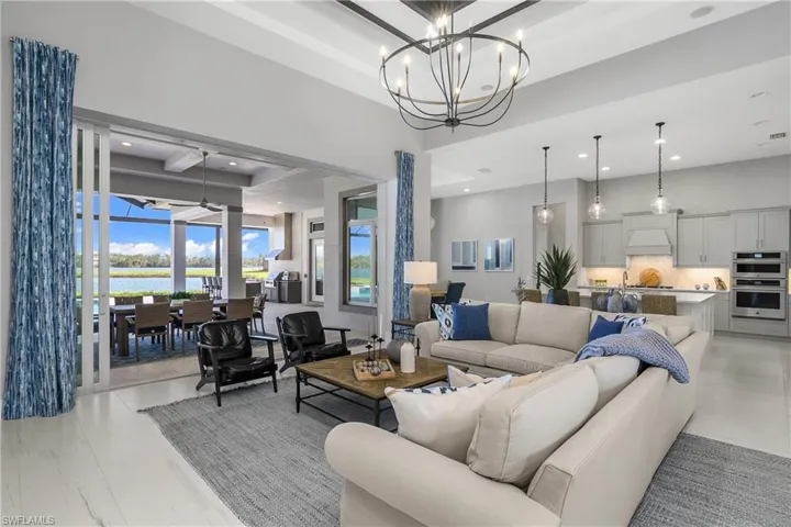 Great room is open and features custom window treatments, designer lighting, detailed woodwork and finishes, and a seamless transition from indoor to outdoor living.