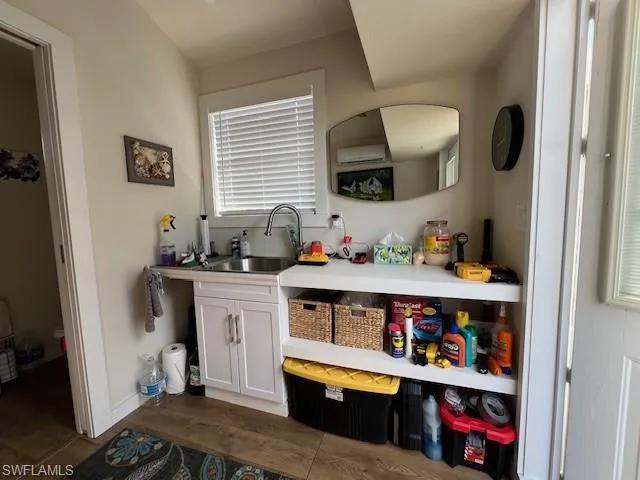 Kitchen featuring light countertops, a sink, dark wood-style floors, baseboards, and white cabinets