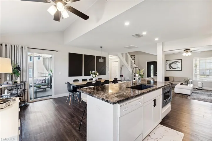 Kitchen with a kitchen breakfast bar, white dishwasher, sink, white cabinetry, and lofted ceiling