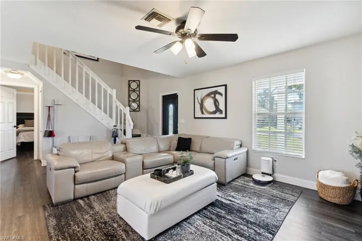 Living room with dark hardwood / wood-style floors and ceiling fan
