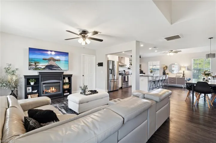 Living room with ceiling fan and dark wood-type flooring