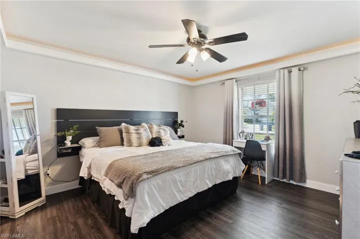 Bedroom featuring ceiling fan, dark wood-type flooring, and ornamental molding